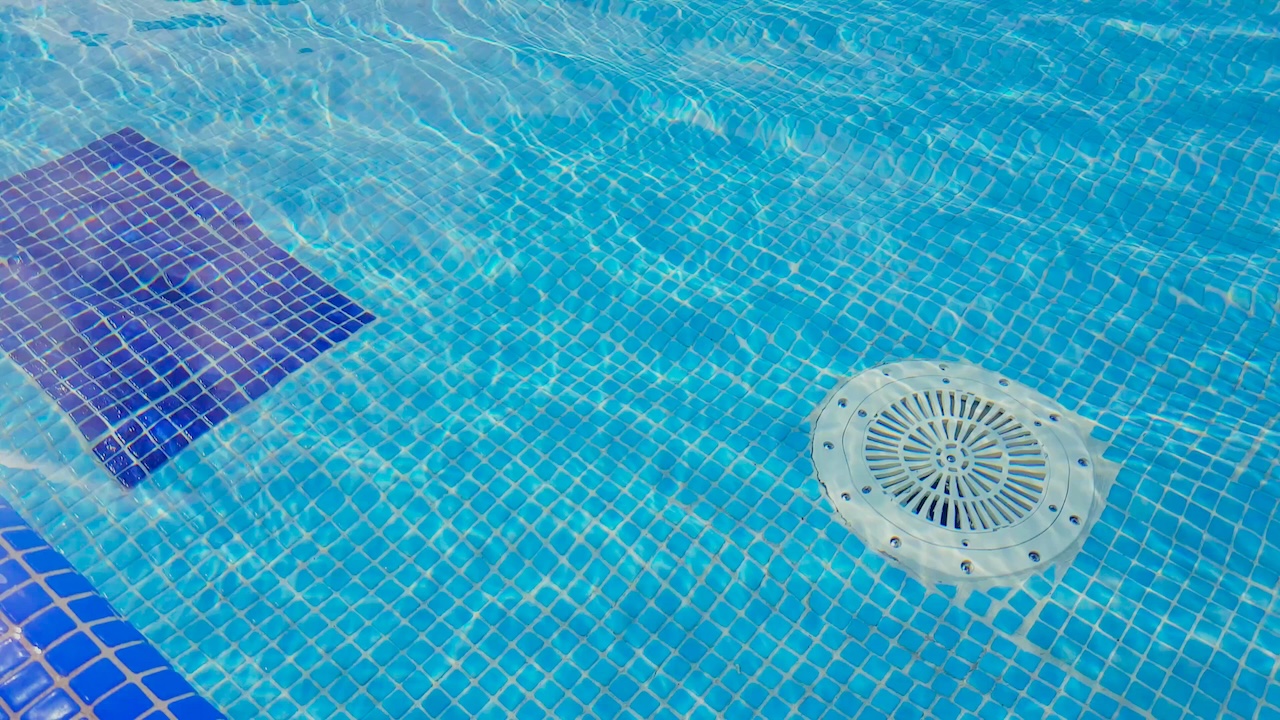 Cleaning of the drain valve filter at the bottom of the swimming pool, movement of clear water, top view.