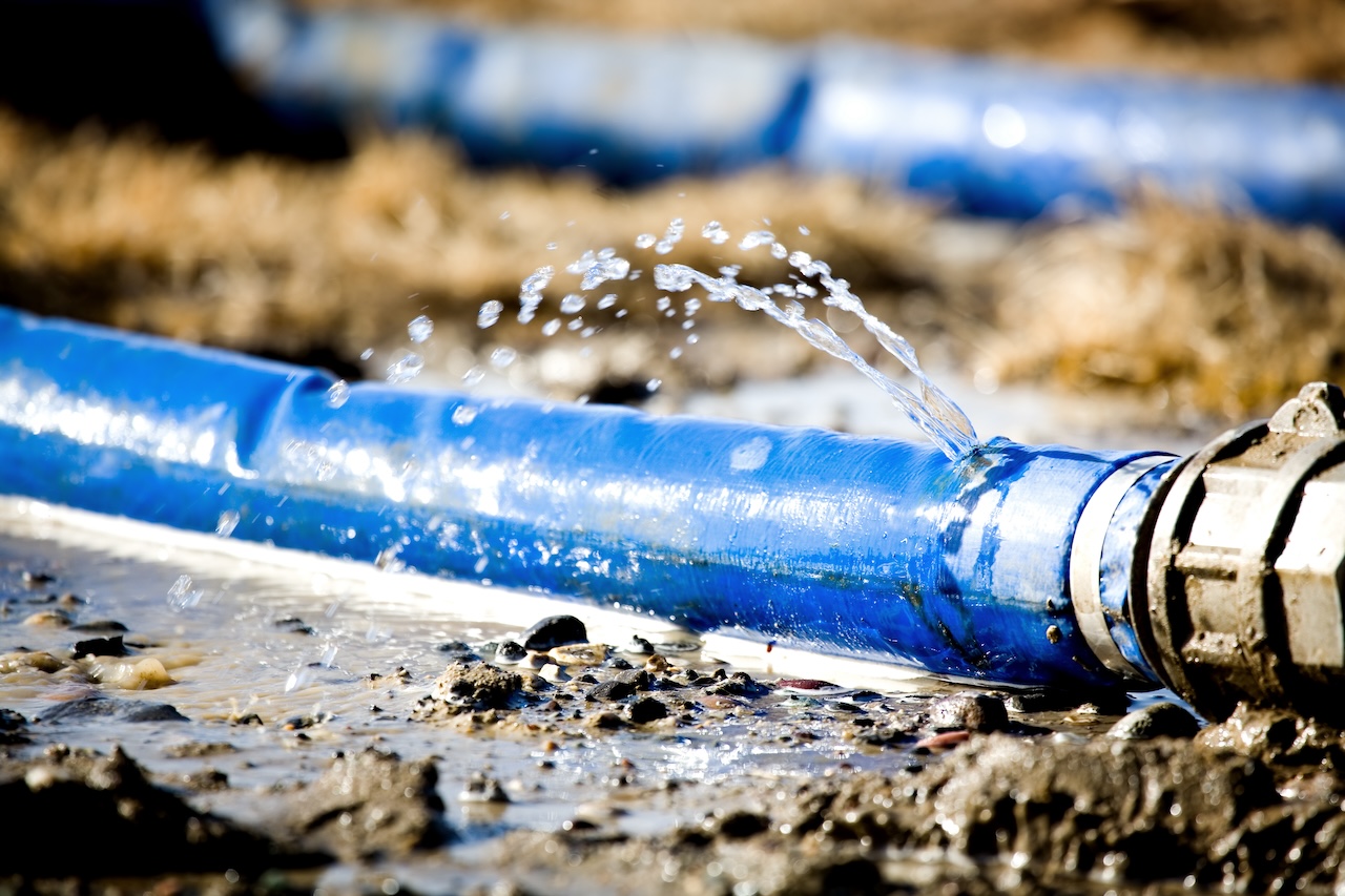 wasting water - water leaking from a hole in a hose. shallow dof with focus on pool hose leak